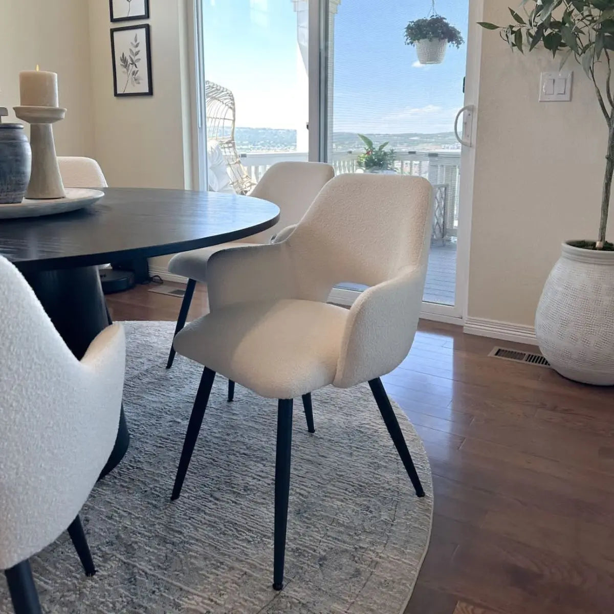 Edwin Upholstered Dining Chair with Arms, white round table, light wood floor, elegant dining area.