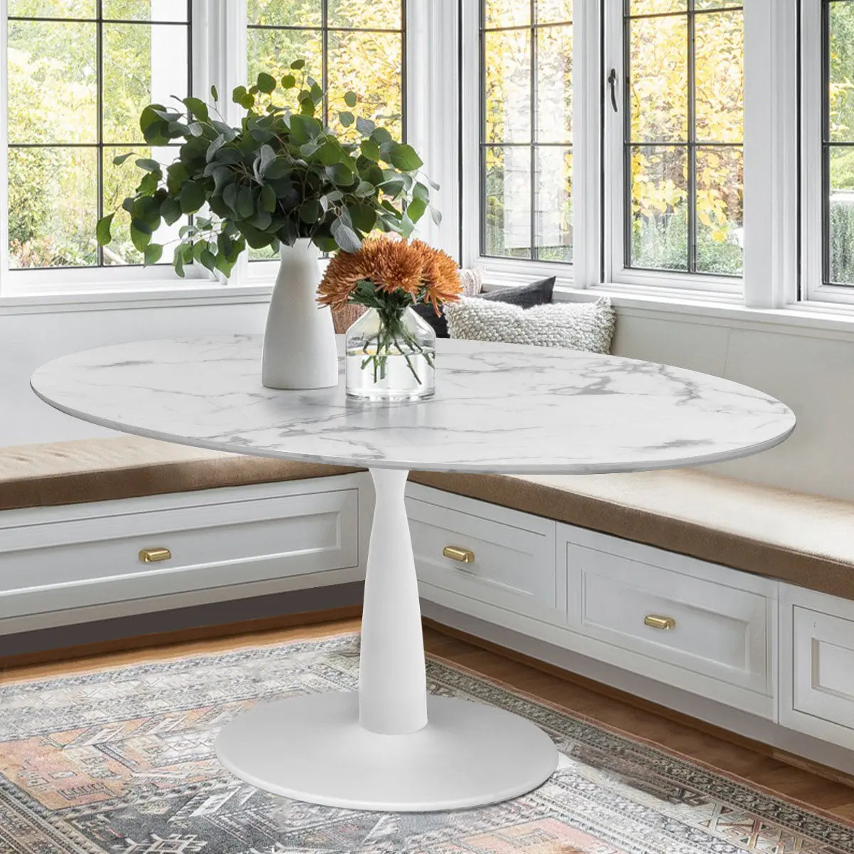 Harris Modern Oval Marble Dining Table in bright dining room with white cabinetry and patterned rug.