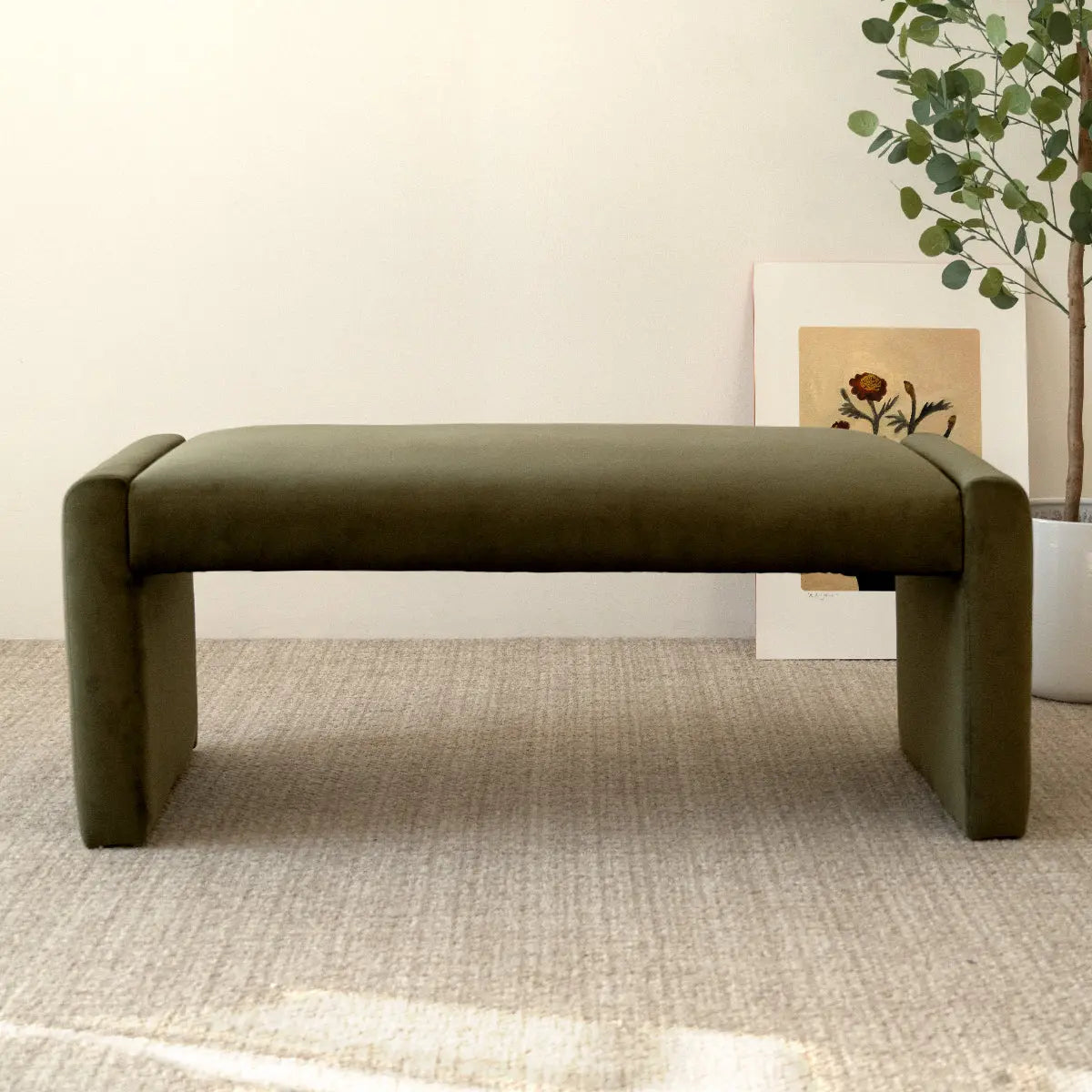 Kaia Modern Bench in olive velvet on beige carpet; minimalist room with artwork and greenery.