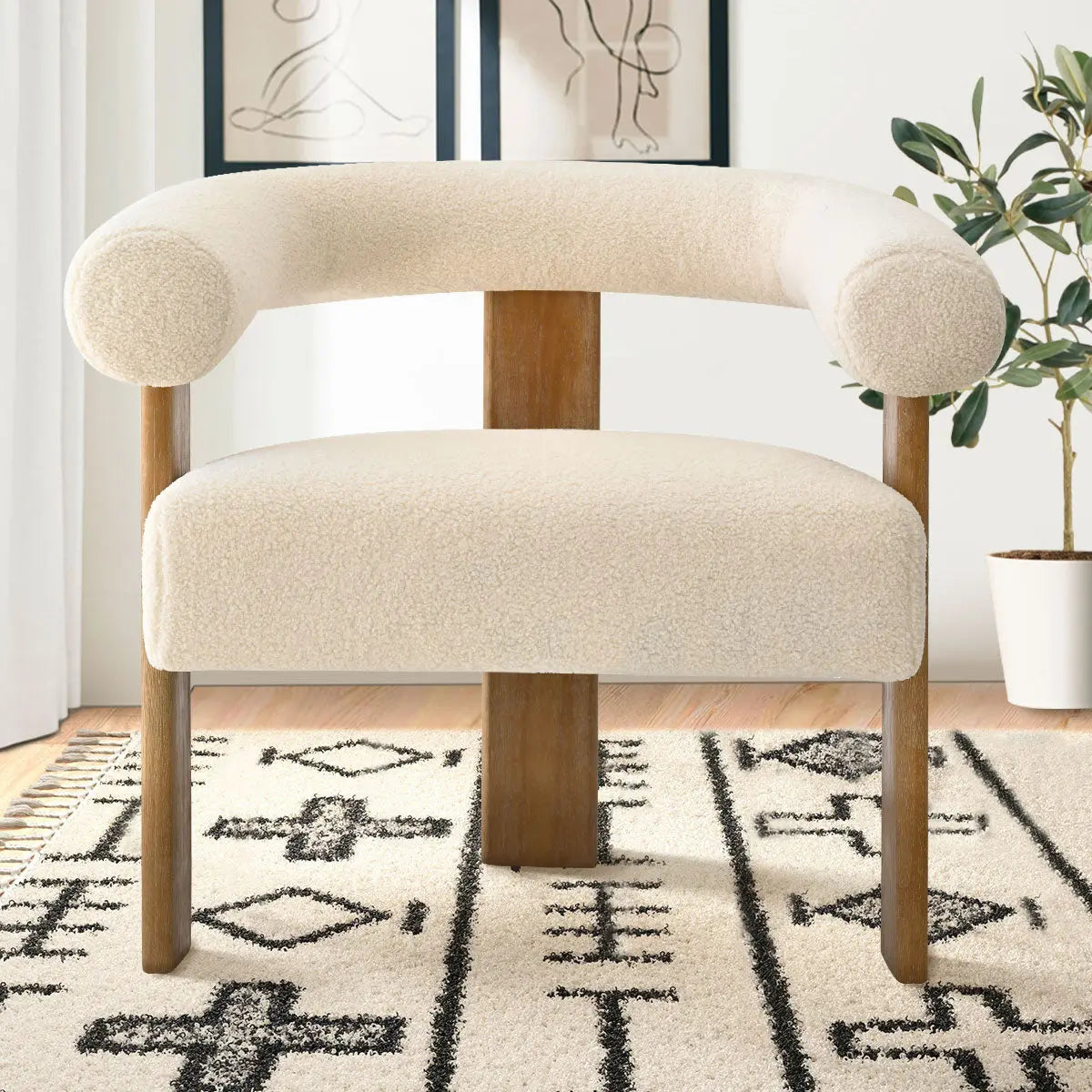 Maye beige boucle chair with wooden legs, geometric rug, artwork, light wall, and wood flooring.