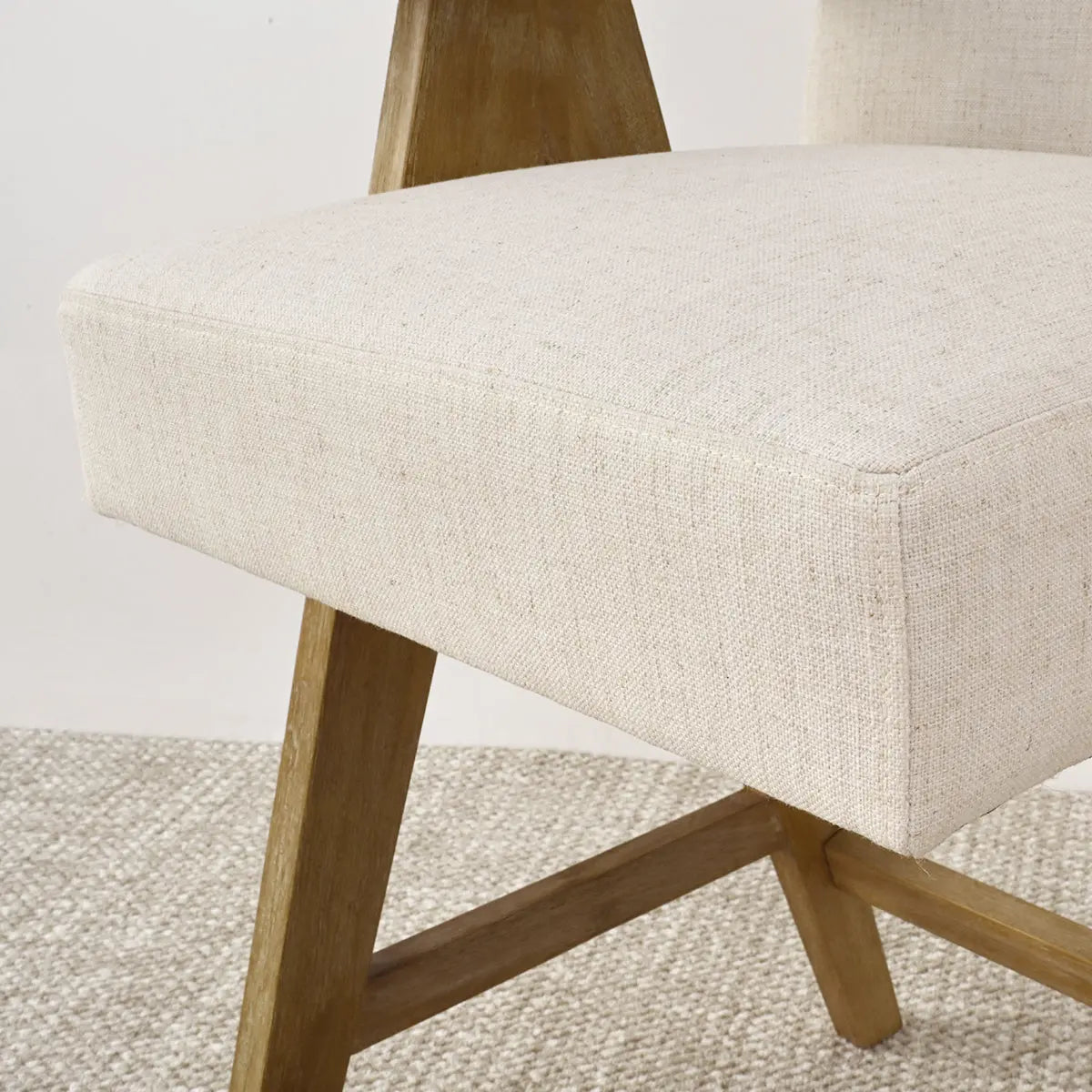Morgan mid-century modern stool with arms, beige upholstery, wooden legs, textured carpet flooring.