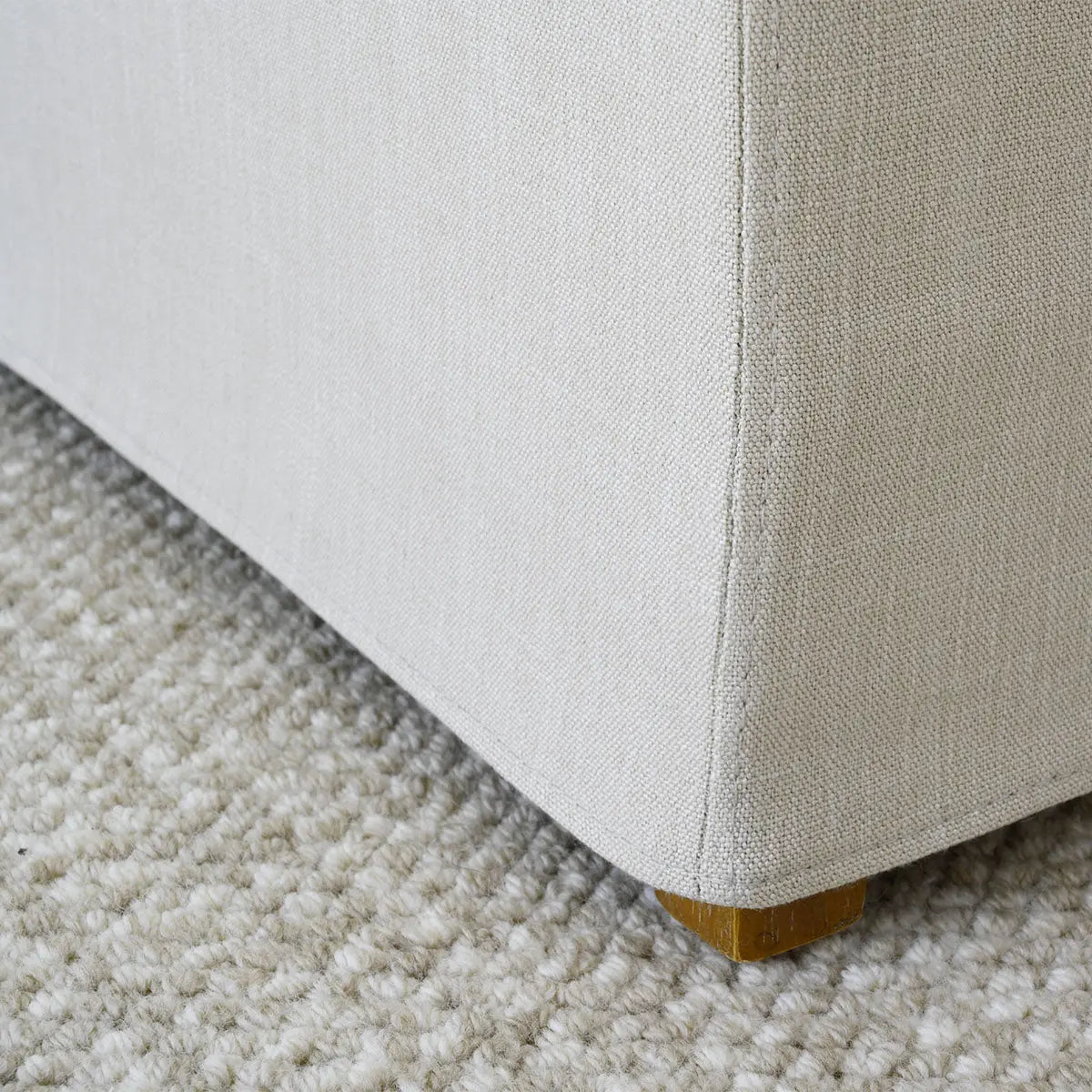 Close-up of North Beige Dining Chair corner on textured carpet flooring, showcasing fabric and wood detail.