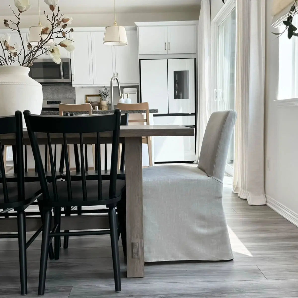 North Beige dining chair in kitchen with white cabinets, black chairs, oak table, and light flooring.