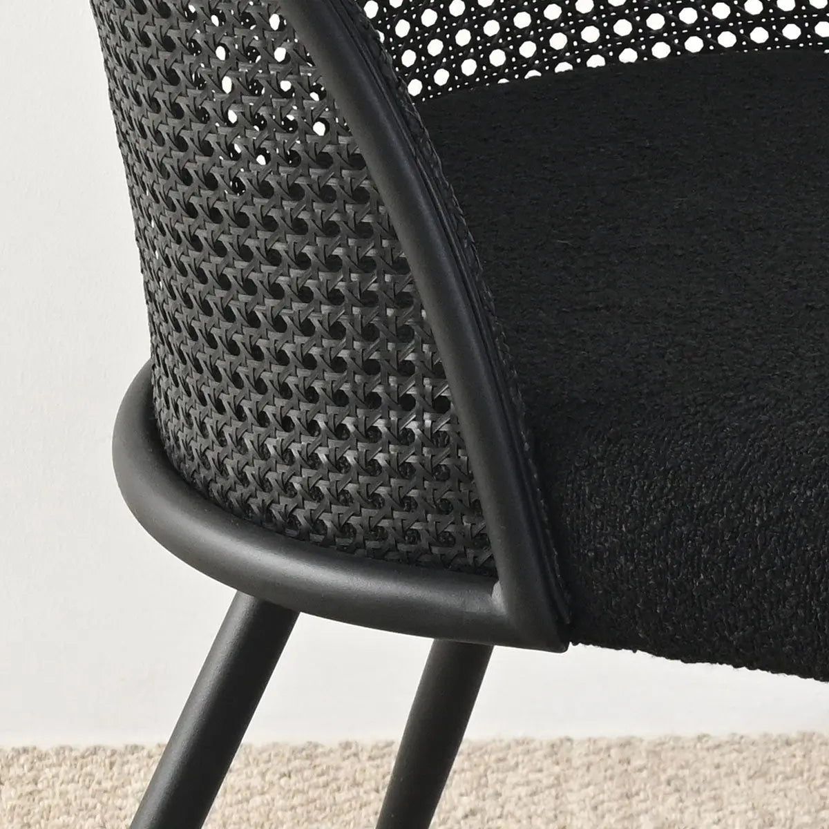 Lucca Black Rattan Boucle Dining Chair close-up with woven backrest on neutral flooring.