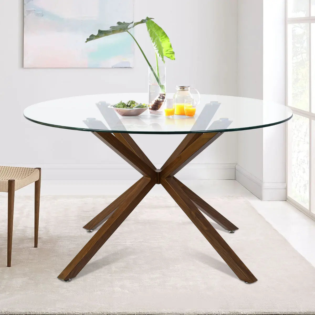 Oliver Modern Round Glass Dining Table, wooden legs, beige rug, white wall, and natural light.