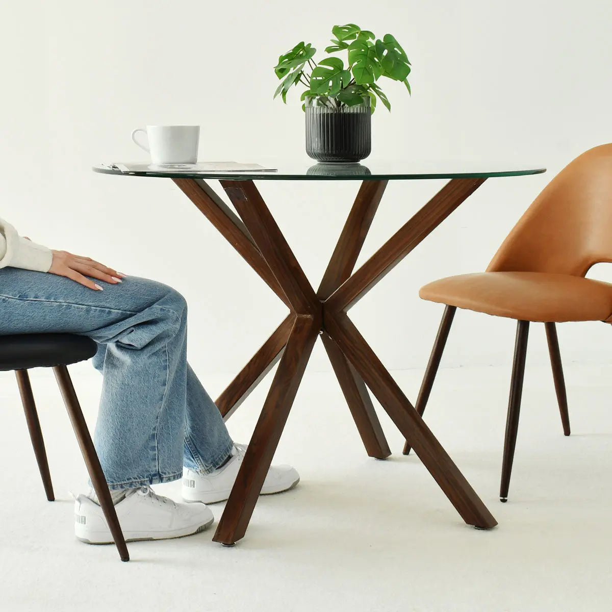 Oliver Modern Round Glass Dining Table, brown legs, beige chair, white flooring, dining room setting.
