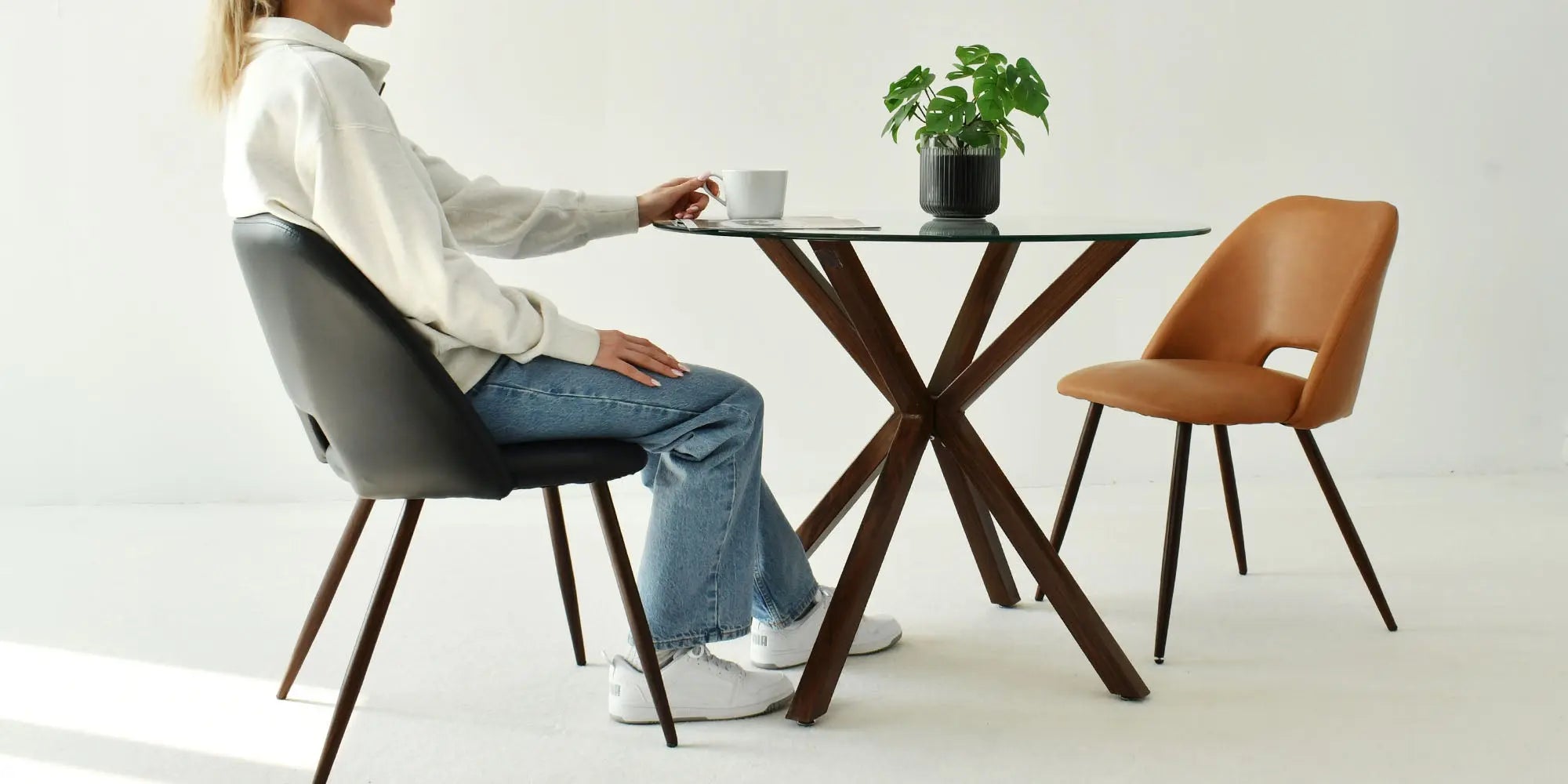 Oliver Modern Round Glass Dining Table, black and tan chairs, white walls, dining room setting.